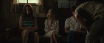 Movie still from “The Glass Castle” (2017), directed by Destin Daniel Cretton – A girl sitting on a couch between two other people; Medium shot, Low angle