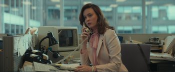 Movie still from “The Glass Castle” (2017), directed by Destin Daniel Cretton – A woman sitting at a desk talking on the phone; Medium shot, Over the shoulder angle