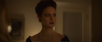 Movie still from “The Glass Castle” (2017), directed by Destin Daniel Cretton – A woman wearing a dress and pearls in a dark room; Close Up shot, Over the shoulder angle