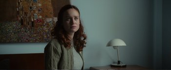 Movie still from “The Glass Castle” (2017), directed by Destin Daniel Cretton – A woman with long red curly hair sitting in front of a lamp; Medium shot, Over the shoulder angle