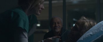 Movie still from “The Good Nurse” (2022), directed by Tobias Lindholm – A group of people sitting at a table talking to each other; Medium shot, Over the shoulder angle