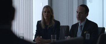 Movie still from “The Good Nurse” (2022), directed by Tobias Lindholm – A woman sitting in front of a table with a glass of water; Medium shot, Over the shoulder angle