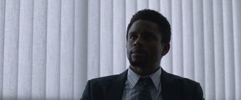 Movie still from “The Good Nurse” (2022), directed by Tobias Lindholm – A man wearing a suit and tie in front of a window; Close Up shot, Low angle