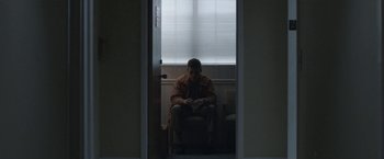 Movie still from “The Good Nurse” (2022), directed by Tobias Lindholm – A man sitting in a chair in a room; Wide shot, Low angle
