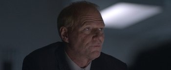 Movie still from “The Good Nurse” (2022), directed by Tobias Lindholm – An older man wearing a suit and tie looking to his left; Close Up shot, Low angle