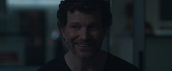 Movie still from “The Good Nurse” (2022), directed by Tobias Lindholm – A person with curly hair smiling; Close Up shot, Over the shoulder angle