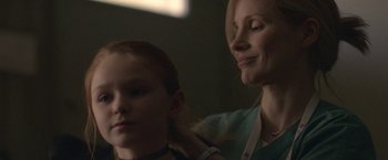 Movie still from “The Good Nurse” (2022), directed by Tobias Lindholm – A woman is putting a necklace on a young girl's neck; Close Up shot, Over the shoulder angle