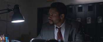 Movie still from “The Good Nurse” (2022), directed by Tobias Lindholm – A man wearing a suit and tie looking off into the distance; Close Up shot, Over the shoulder angle