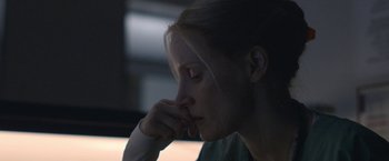 Movie still from “The Good Nurse” (2022), directed by Tobias Lindholm – A woman sitting in the dark with her head resting on her hand; Close Up shot, Low angle