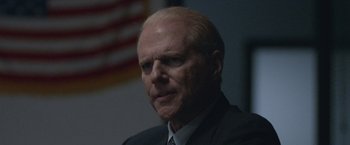 Movie still from “The Good Nurse” (2022), directed by Tobias Lindholm – An older man in a suit and tie looking at the camera; Close Up shot, Over the shoulder angle