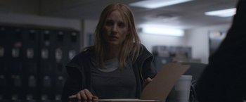 Movie still from “The Good Nurse” (2022), directed by Tobias Lindholm – A woman sitting at a table in a dark room; Medium shot, Over the shoulder angle