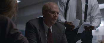 Movie still from “The Good Nurse” (2022), directed by Tobias Lindholm – A man in a suit and tie sitting down; Close Up shot, Over the shoulder angle
