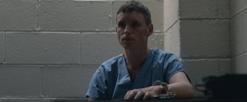 Movie still from “The Good Nurse” (2022), directed by Tobias Lindholm – A man in a blue shirt is sitting at a table; Close Up shot, Low angle