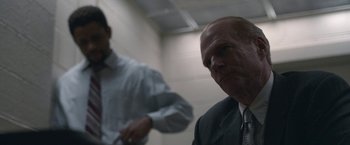 Movie still from “The Good Nurse” (2022), directed by Tobias Lindholm – A man in a suit and tie standing next to another man in a suit and tie; Close Up shot, Over the shoulder angle