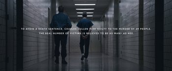 Movie still from “The Good Nurse” (2022), directed by Tobias Lindholm – Two men walking down a hall way in a building; Wide shot, High angle