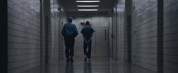 Movie still from “The Good Nurse” (2022), directed by Tobias Lindholm – Two men are walking down a hallway in a building; Wide shot, Low angle