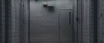 Movie still from “The Good Nurse” (2022), directed by Tobias Lindholm – A door in a room with a brick wall; Extreme Wide shot, Low angle