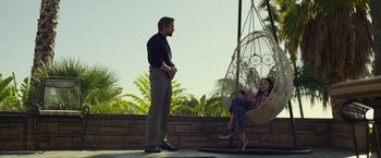 Movie still from “The Gray Man” (2022), directed by Joe Russo – A man and a woman sitting on a swing; Wide shot, Over the shoulder angle