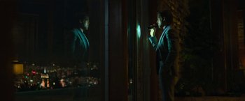 Movie still from “The Gray Man” (2022), directed by Joe Russo – A man standing in front of a mirror holding a microphone; Wide shot, Low angle