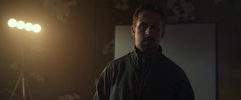 Movie still from “The Gray Man” (2022), directed by Joe Russo – A man standing in a dark room looking at the camera; Close Up shot, Low angle