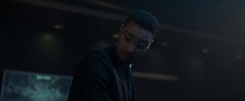 Movie still from “The Gray Man” (2022), directed by Joe Russo – A man in a suit and glasses looking down; Close Up shot, Over the shoulder angle