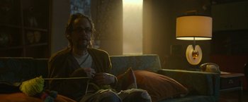 Movie still from “The Gray Man” (2022), directed by Joe Russo – A man sitting on top of a couch knitting; Medium shot, Low angle