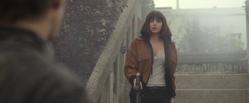 Movie still from “The Gray Man” (2022), directed by Joe Russo – A woman holding a gun while standing next to a tree; Medium shot, Over the shoulder angle