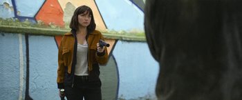 Movie still from “The Gray Man” (2022), directed by Joe Russo – A woman holding a remote control in her hand; Medium shot, Over the shoulder angle