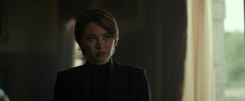 Movie still from “The Gray Man” (2022), directed by Joe Russo – A woman wearing a black jacket standing next to a window; Close Up shot, Low angle