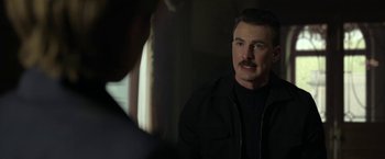 Movie still from “The Gray Man” (2022), directed by Joe Russo – A man in a black jacket is looking at himself in the mirror; Close Up shot, Over the shoulder angle