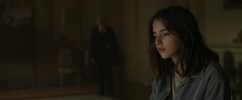 Movie still from “The Gray Man” (2022), directed by Joe Russo – A young woman is sitting in a dark room; Close Up shot, Low angle