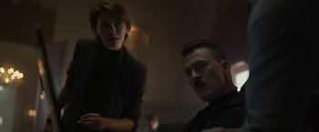 Movie still from “The Gray Man” (2022), directed by Joe Russo – A man and a woman are sitting in a room together; Medium shot, Low angle