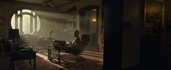 Movie still from “The Gray Man” (2022), directed by Joe Russo – A man sitting at a table in a room; Wide shot, High angle