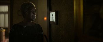 Movie still from “The Gray Man” (2022), directed by Joe Russo – An older woman standing in front of a television; Close Up shot, Over the shoulder angle