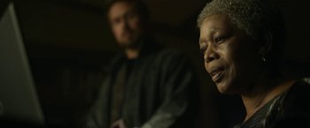 Movie still from “The Gray Man” (2022), directed by Joe Russo – An older man and a younger man in a dark room; Close Up shot, Over the shoulder angle