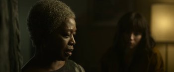 Movie still from “The Gray Man” (2022), directed by Joe Russo – An older woman is looking into the distance; Close Up shot, Over the shoulder angle