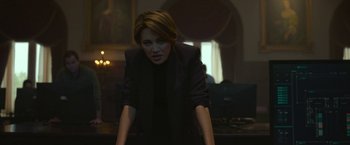 Movie still from “The Gray Man” (2022), directed by Joe Russo – A woman in a black jacket standing in front of a window; Medium shot, Low angle