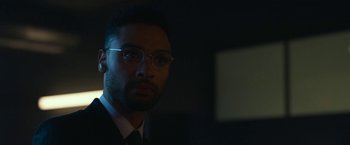 Movie still from “The Gray Man” (2022), directed by Joe Russo – A person wearing a suit and glasses; Close Up shot, Low angle