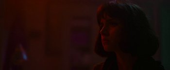 Movie still from “The Gray Man” (2022), directed by Joe Russo – A woman is looking into the distance in a dark room; Close Up shot, Over the shoulder angle