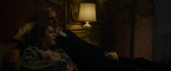 Movie still from “The Gray Man” (2022), directed by Joe Russo – A man and a woman sitting on a couch in a living room; Medium shot, High angle