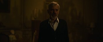 Movie still from “The Gray Man” (2022), directed by Joe Russo – An older man in a black jacket and a white shirt; Medium shot, Over the shoulder angle