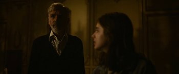 Movie still from “The Gray Man” (2022), directed by Joe Russo – An older man and a young woman in a dark room; Medium shot, Over the shoulder angle