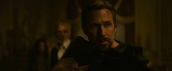 Movie still from “The Gray Man” (2022), directed by Joe Russo – A man in a dark room looking at the camera; Close Up shot, Over the shoulder angle