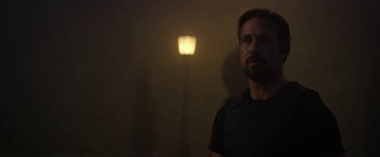 Movie still from “The Gray Man” (2022), directed by Joe Russo – A man standing next to a street light in the dark; Close Up shot, Low angle