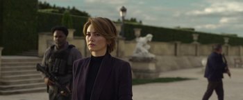 Movie still from “The Gray Man” (2022), directed by Joe Russo – A woman in a black jacket standing in front of a statue; Medium shot, Over the shoulder angle