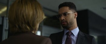 Movie still from “The Gray Man” (2022), directed by Joe Russo – A man in a suit talking to a woman in a suit; Close Up shot, Over the shoulder angle