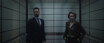 Movie still from “The Gray Man” (2022), directed by Joe Russo – A man and a woman standing next to each other in front of a wall; Medium shot, Low angle