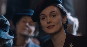 Movie still from “The Guernsey Literary and Potato Peel Pie Society” (2018), directed by Mike Newell – A person wearing a hat; Close Up shot, Over the shoulder angle