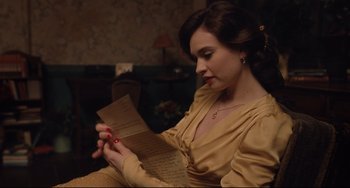 Movie still from “The Guernsey Literary and Potato Peel Pie Society” (2018), directed by Mike Newell – A woman sitting in a chair holding an envelope; Close Up shot, Over the shoulder angle