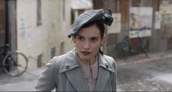 Movie still from “The Guernsey Literary and Potato Peel Pie Society” (2018), directed by Mike Newell – A woman wearing a hat and a jacket; Close Up shot, Over the shoulder angle